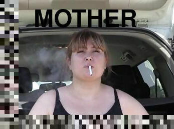 A cute bbw smokes in the street near the car