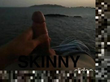 Skinny guy masturbates on a cliff during a sunset in Ibiza