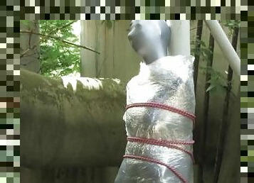 Bondaged and cocooned slave girl in the mystery garden - Full encasement fetish in zentai body bag